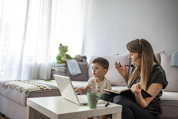 Mother working from home with kid. Children make noise and disturb woman at work. Homeschooling and freelance job. Moms Can Balance Work and Family. Multitasking mother working from home.  - Foto, imagen