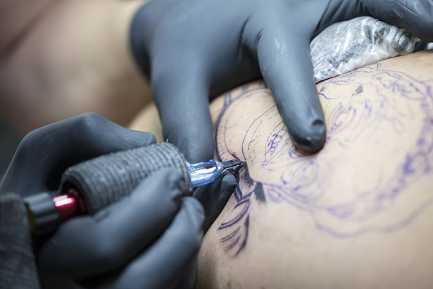 tatoeage in proces, tattoo machine met zijn naalden prikken inkt op de huid. - Foto, afbeelding