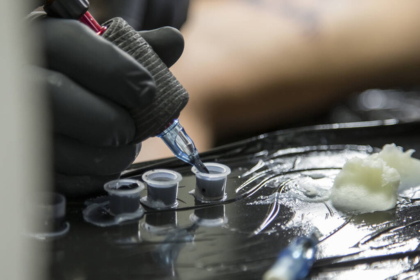 Riempimento dell'inchiostro sulla macchina del tatuaggio durante una sessione
. - Foto, immagini