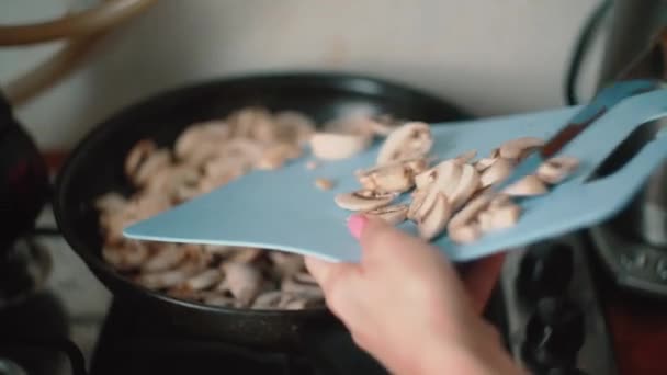 pour chopped mushrooms into pan with knife - Felvétel, videó