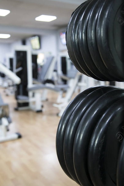 Cerrar los discos de peso en su soporte vertical en la sala de fitness de gimnasios
. - Foto, Imagen
