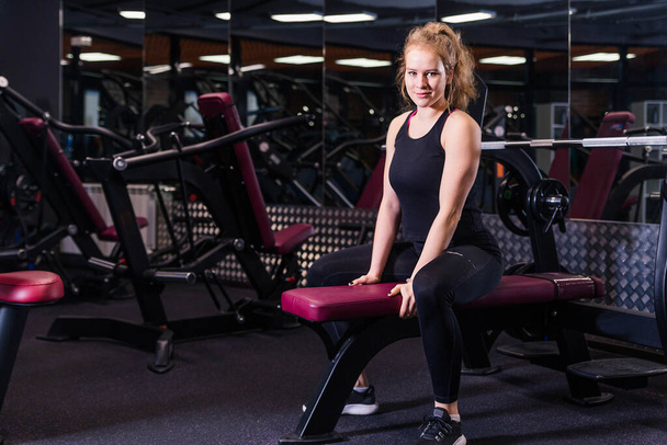 Femme bodybuilder blonde est assis dans la salle de gym sur le banc. Photo horizontale
 - Photo, image