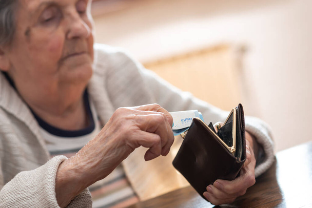 Elderly woman taking out a banknote from her wallet - Fotó, kép