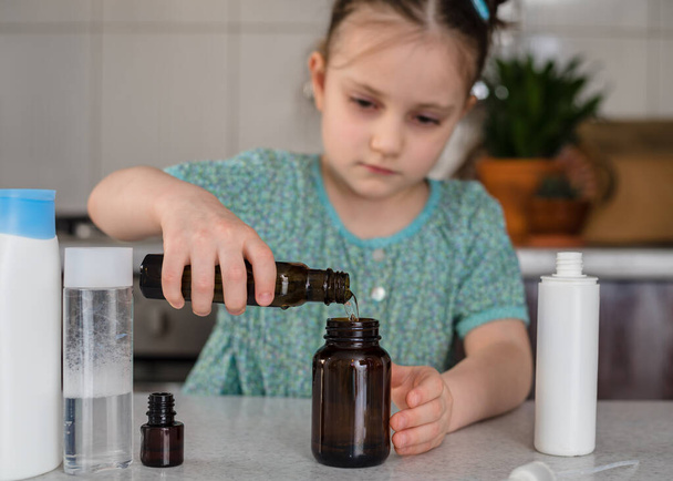 子供の女の子は自宅で消毒剤や防腐剤ゲルを作ります。コロナウイルスの流行中の衛生状態。安全生活の概念。Covid-19パンデミック - 写真・画像