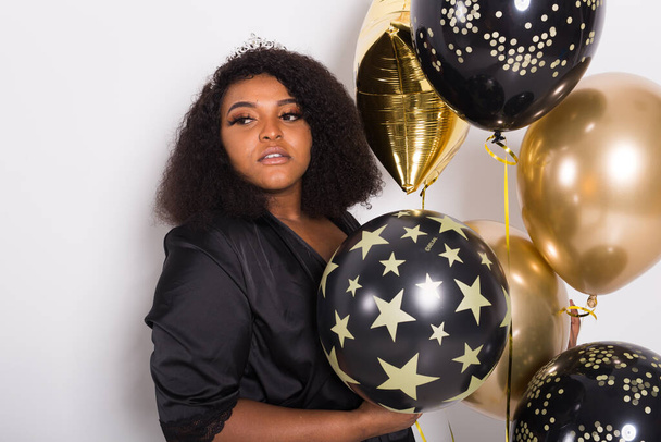 休日、誕生日パーティーや楽しいコンセプト-笑顔の若いアフリカ系アメリカ人の若い女性の肖像画白い背景に風船を保持スタイリッシュな見て. - 写真・画像