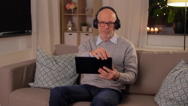 senior man with tablet pc and headphones at home - Filmmaterial, Video