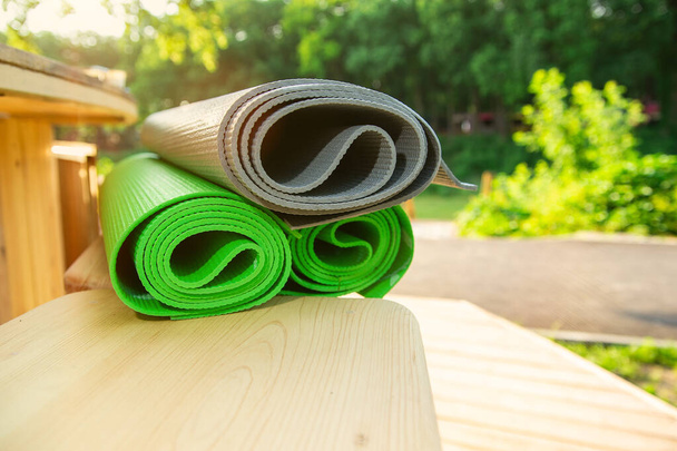 three roll-up sports mats on a wooden floor in a park outside with the setting summer sun - Foto, Imagem
