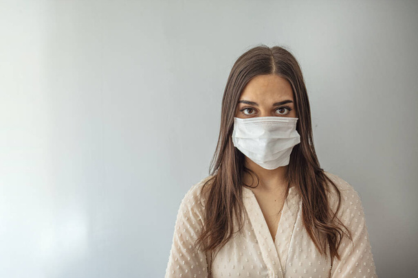 Woman in a medical mask close-up on a gray background. Healthy lifestyle, ill sick disease treatment concept. Mock up copy space. epidemic, dangerous and deadly virus, infection concept - Fotografie, Obrázek