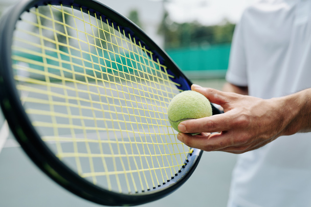 Nahaufnahme eines Tennisspielers, der Schläger und Ball in der Hand hält und sich zum Aufschlag bereit macht - Foto, Bild