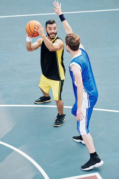 Sorrindo esportista hispânico curtindo jogar basquete com amigo - Foto, Imagem