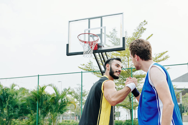 Basketball players shaking hands after playing game together on outdoors court - Photo, Image