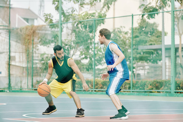 Młodzi sportowcy grają w koszykówkę na boisku zewnętrznym - Zdjęcie, obraz