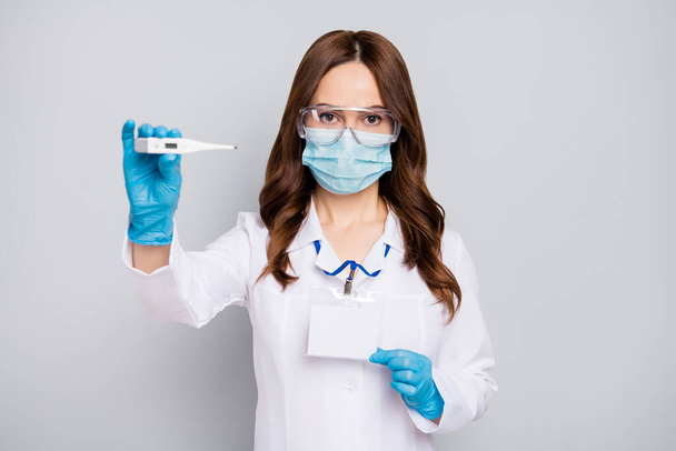 Portrait of her she nice attractive confident wavy-haired doc expert wearing goggles showing digital device measuring temperature hospital service isolated over grey pastel color background - Foto, imagen