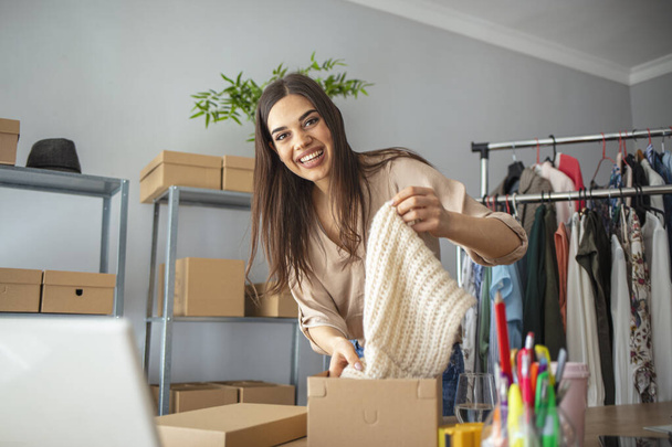Young woman selling products online and packaging goods for shipping. Women, owener of small business packing product in boxes, preparing it for delivery - Valokuva, kuva