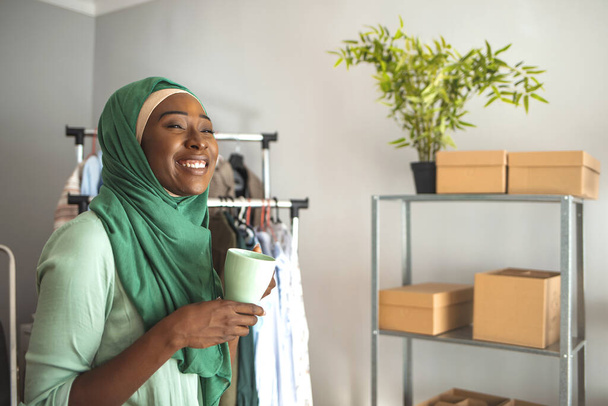 Muslim Businesswomen with Coffee Cup. Muslim woman designer as a startup business owner drinking coffee at her shop. A Middle-eastern woman is indoors in her home office - Foto, Bild