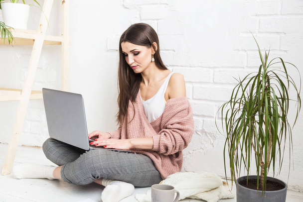 Young woman sits on the floor in a Scandinavian apartment interior with a laptop, studying law, freelance girl at work, distance learning student, online employment, paperwork and outsourcing concept - Φωτογραφία, εικόνα