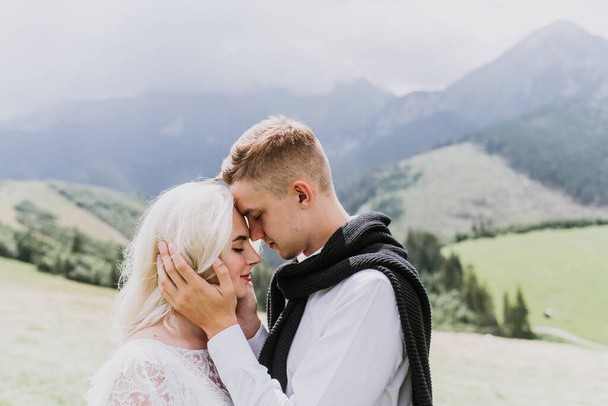 Beautiful bride in a boho style dress and groom hug and kiss in the mountains. - Fotografie, Obrázek