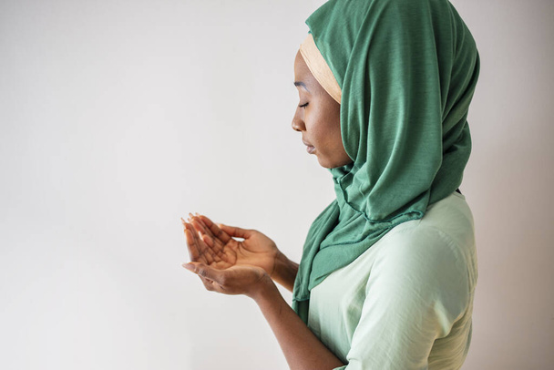 Close up picture of a young muslim woman praying. Young Muslim woman Praying with folded hands. She has a green veil covering her head. Young muslim woman praying in mosque - Valokuva, kuva