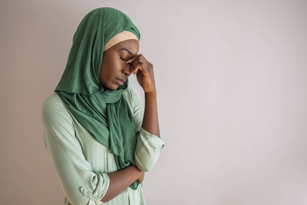 Muslim woman having a severe headache. Female office worker tired and feel bad. Stress and health. Young woman posing looking down with her hand in her head serious, sad, with a headache - Φωτογραφία, εικόνα