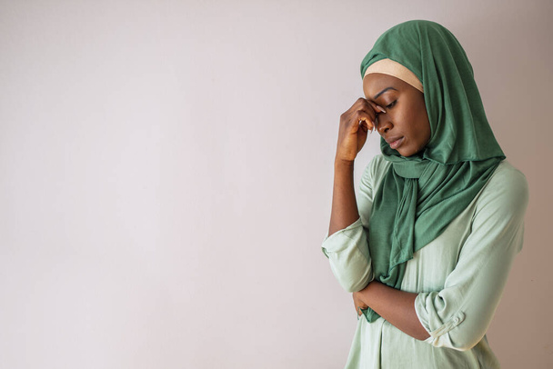 Muslim woman having a severe headache. Female office worker tired and feel bad. Stress and health. Young woman posing looking down with her hand in her head serious, sad, with a headache - Foto, Imagem