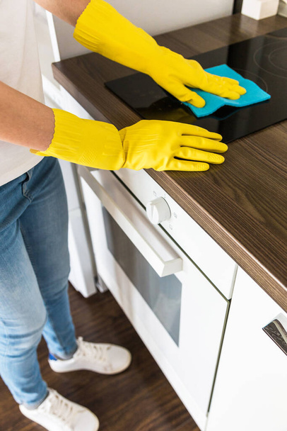 A young woman from a professional cleaning company cleans up at home. A man washes the kitchen in yellow gloves with cleaning supplies stuff. - 写真・画像