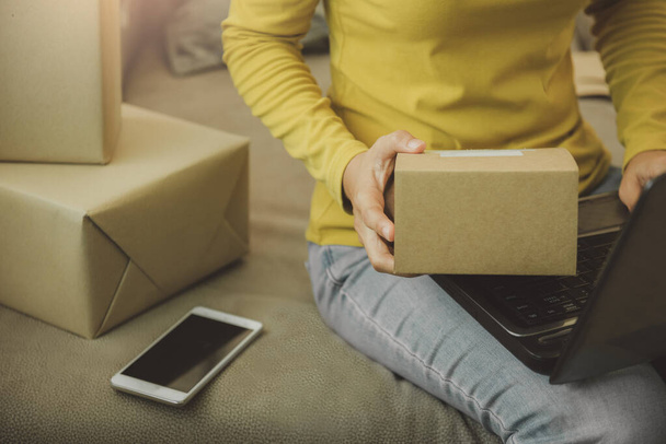 Woman holds a box to prepare to deliver to the customer according to the order at home.Work from home and marketing online or startup small business concept.with copy space. - Zdjęcie, obraz