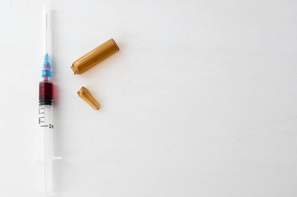 Jeringa con medicamento rojo y ampolla usada
 - Foto, Imagen