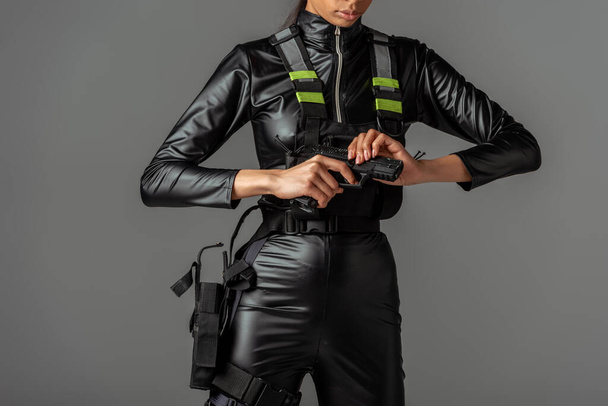 levágott kilátás futurisztikus afro-amerikai nő újratöltő fegyver elszigetelt szürke - Fotó, kép