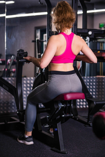 Urheilullinen nainen vaaleanpunainen alkuun kaunis kehon käyttäessään rakennuksen lihaksia. Pystysuora valokuva
 - Valokuva, kuva