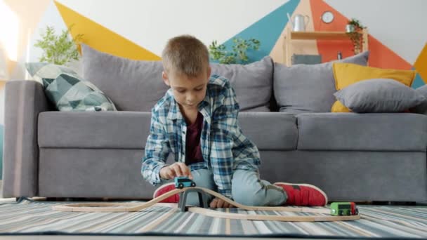 Безтурботний хлопчик грає з іграшковими машинами в квартирі насолоджуючись грою на підлозі в будинку
 - Кадри, відео