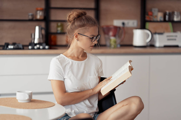 Cute girl is drinking coffee and reading a book - Foto, Imagen