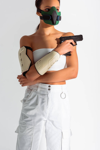 futuristic african american woman in safety mask with gun isolated on white - 写真・画像