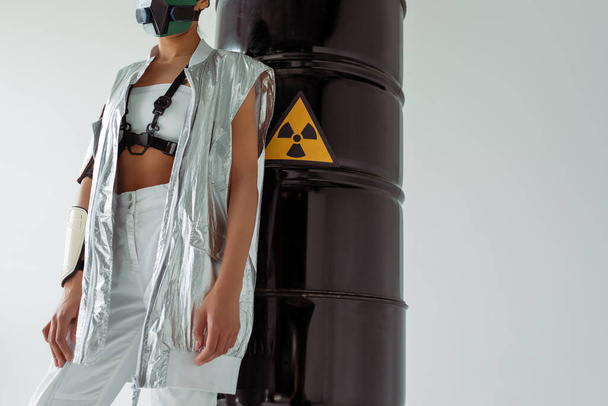cropped view of futuristic african american woman in safety mask near radioactive waste barrels isolated on white - Zdjęcie, obraz