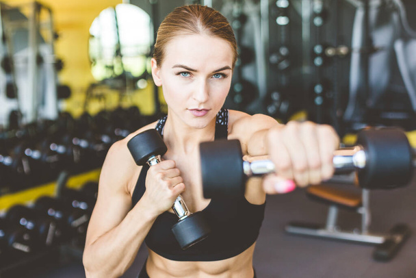 Working out with dumbbell weights at the gym.Fitness Women exercising are lifting dumbbells. Fitness muscular body.Workout at gym. - 写真・画像