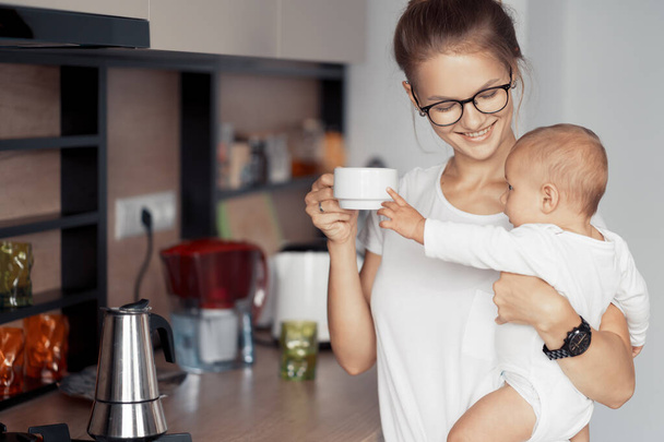 Young mother with baby in the kitchen - Photo, Image
