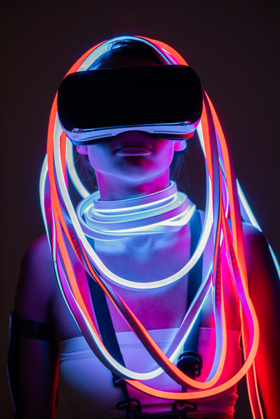 VR kulaklıklı ve neon ışıklı fütürist Afrikalı Amerikalı kadın. - Fotoğraf, Görsel