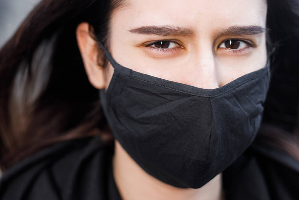 Young woman wearing face mask. Handsome woman in black hoodie wear black medical mask. Pandemic coronavirus covid-19 quarantine period concept. - Fotoğraf, Görsel