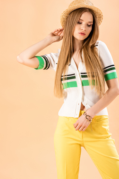 beautiful fashionable girl posing in yellow trousers, polo and straw hat on beige - Foto, Imagem