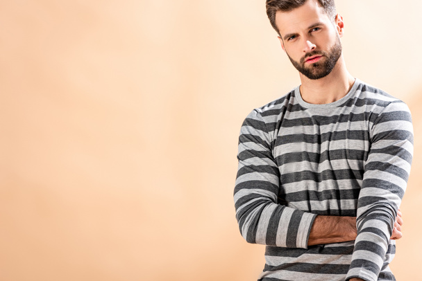 handsome stylish young man posing in striped sweatshirt on beige - Zdjęcie, obraz