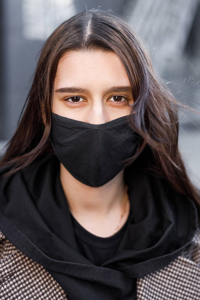 Young woman wearing face mask. Handsome woman in black hoodie wear black medical mask. Pandemic coronavirus covid-19 quarantine period concept. - Photo, image
