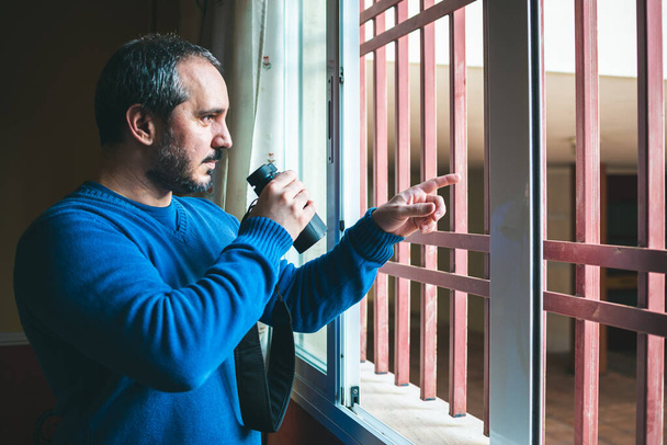 uomo che osserva i vicini attraverso la finestra durante la quarantena
 - Foto, immagini