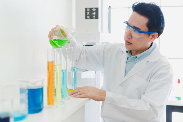 Asiatische Wissenschaftler bereiten Chemikalien für Tests und Analysen im Labor vor. Wissenschaftler räumen Brillen und weiße Hemden ab. Wissenschaft und Chemie-Konzept - Foto, Bild