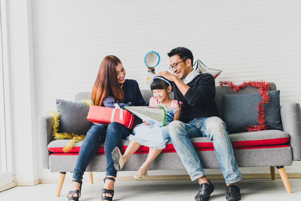 Father, mother and daughter are celebrating Christmas. Christmas hat and a gift for each other. Concept Asian family happiness time. - Foto, afbeelding