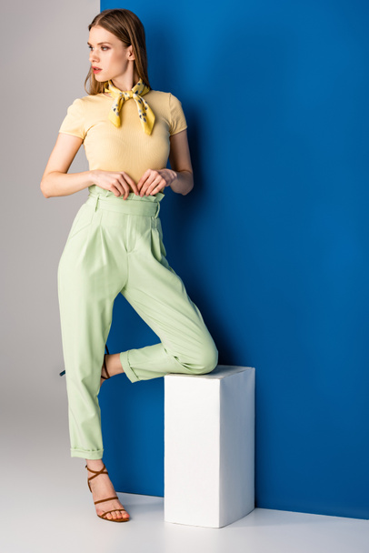 attractive stylish woman posing in green summer trousers and heeled sandals on grey and blue - Фото, зображення