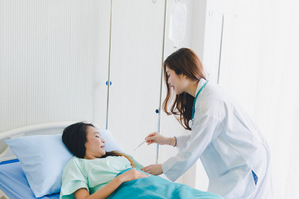 Азійські жінки-лікарі приходять, щоб виміряти температуру пацієнта. Лежачи у ліжку пацієнта. - Фото, зображення