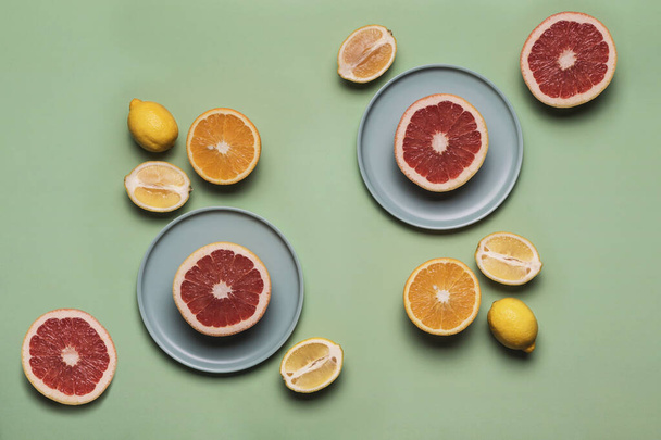 Sinaasappelen, citroenen en grapefruits op een vlakke plaat op een gekleurde lichtgroene ondergrond. Concept van gezonde voeding en vitaminen. Vlak lag met kopieerruimte. Horizontale oriëntatie. - Foto, afbeelding