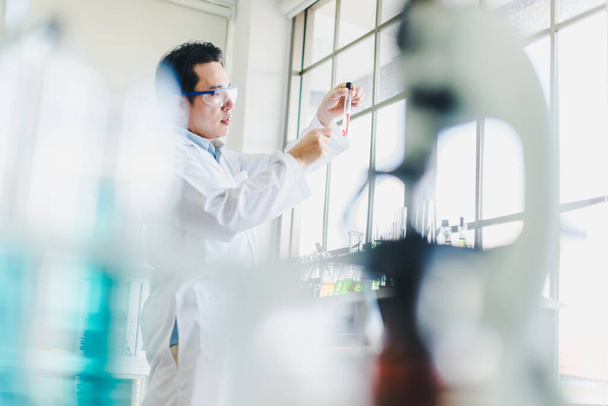 Asian scientists are preparing chemicals for testing and analysis in the laboratory. Scientists clear glasses and white shirts. Science and Chemistry Concept - Foto, Imagen