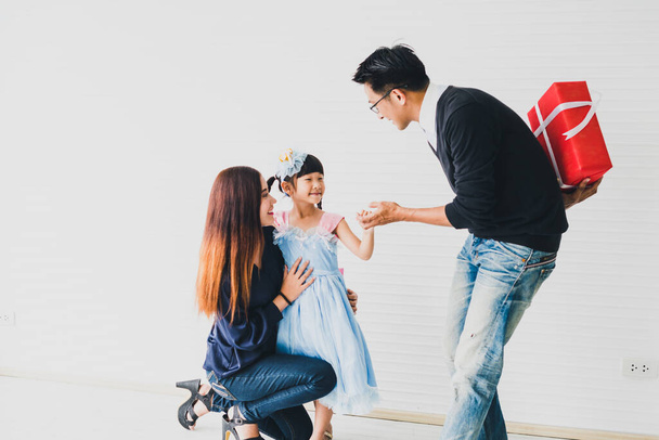 Asian father and mother give a red box gift to daughter on the eve of Christmas and New Year's Day.Family happiness time concept. - Photo, image