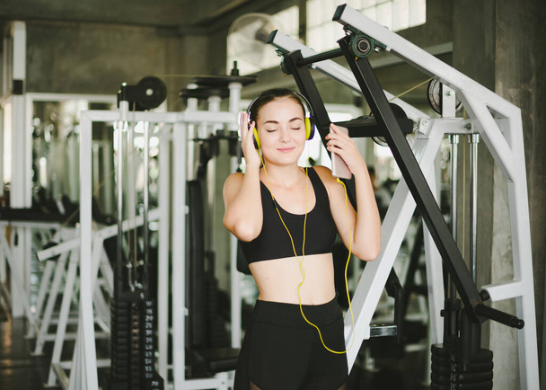 Beautiful women come to exercise in the gym and are relaxed by listening to music from headphones. She wears a sportswear. - Foto, Bild