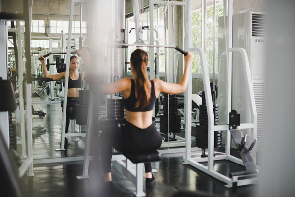 Beautiful athlete exercising with a lat pulldown machine to play the arms and shoulder muscles in the gym. Exercise in the gym concept. - Foto, Imagem